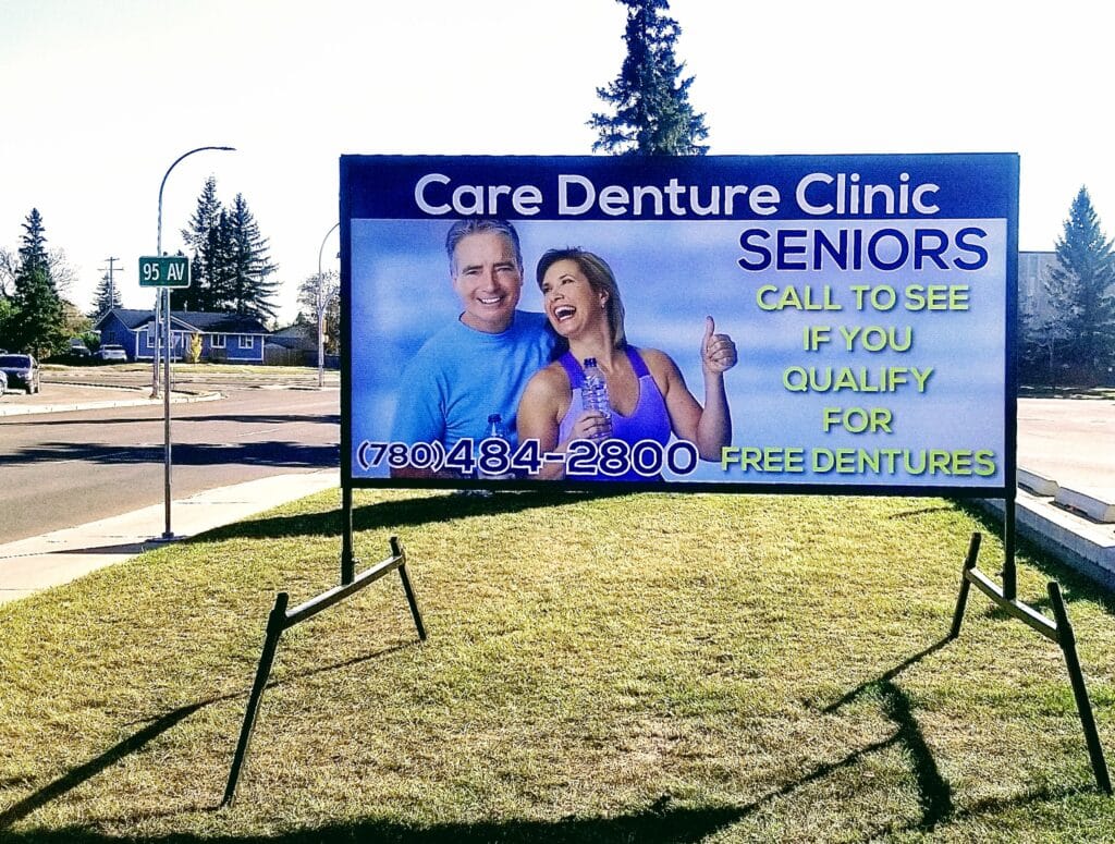 A temporary portable LED sign with a man and a woman on it. Words read Care Denture Clinic: Seniors. Call to see if you qualify for free dentures. 