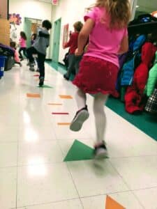 elementary-aged skip down a hallway in a school